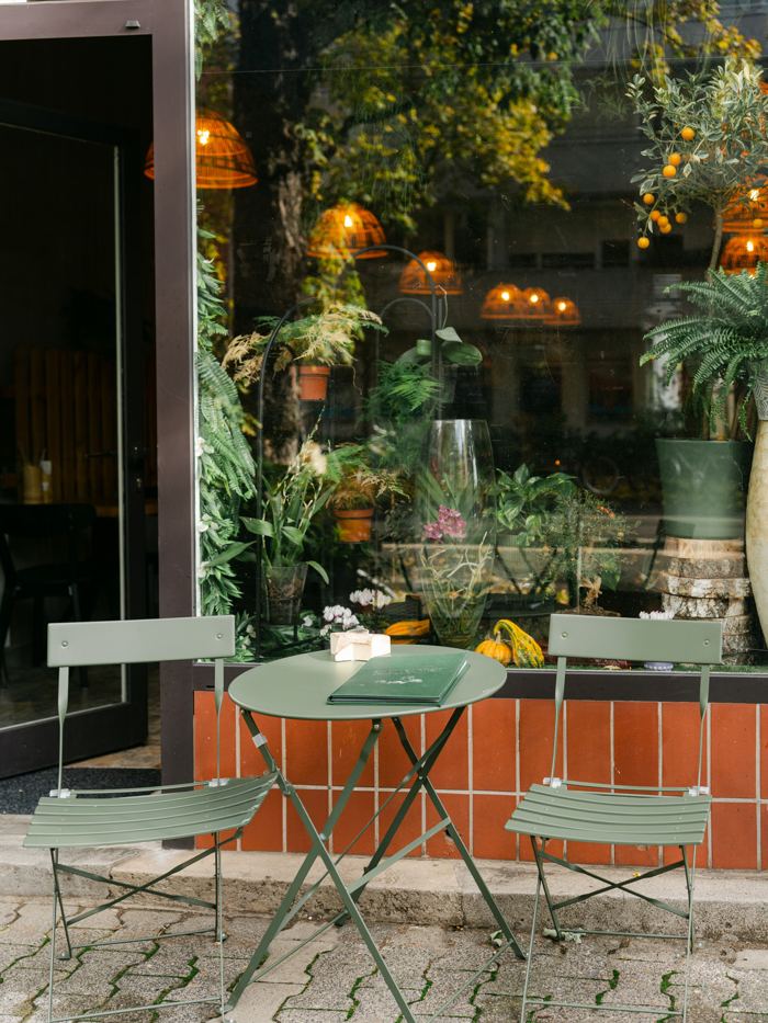 Terrasse mit grünen Bistrotischen vor dem Restaurant