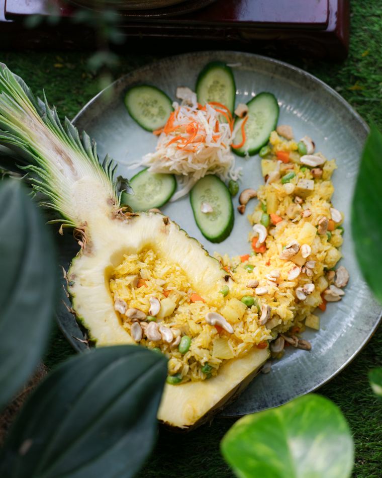 Gebratener Reis in einer ausgehöhlten Ananas mit Gurkenscheiben