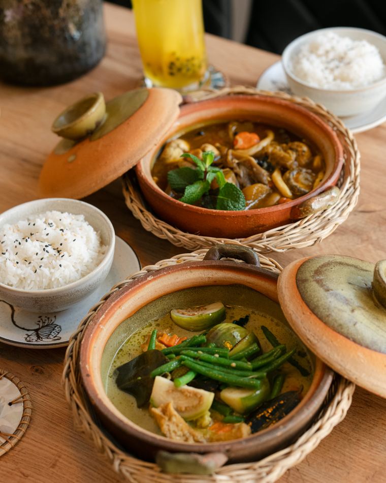 Zwei Tontöpfe mit Curry und Gemüse, dazu Reis und ein Getränk